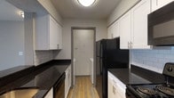 Located at 1480 Runaway Bay Dr in Columbus, Ohio, this single-floor residence offers a well-designed layout with modern finishes throughout. The kitchen is a standout feature, showcasing dark granite countertops, crisp white shaker cabinetry with brushed nickel hardware, a subway tile backsplash, and black appliances including a refrigerator and range. Wood-look vinyl plank flooring runs through the kitchen, which also provides convenient access to an in-unit laundry area. The open living space continues the wood-look flooring and is highlighted by a full-width sliding glass door with vertical blinds that invites natural light and provides views of the surrounding greenery. A peninsula with dark granite connects the kitchen to the main living area, creating an easy flow between spaces. The bedrooms are finished with soft, neutral carpet and feature windows that bring in additional natural light. The bathroom is well-appointed with a white vanity, dark granite countertop, undermount sink, and brushed nickel fixtures, complemented by wood-look flooring and a tub-shower combination. The thoughtful combination of updated finishes and a practical floor plan makes this a comfortable and functional living space.