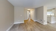 Located at 2519 S Meridian in Puyallup, WA, this one-bedroom, one-bathroom unit offers a thoughtfully arranged single-floor layout that makes efficient use of its space. The living room serves as the heart of the home, highlighted by a classic fireplace with a tiled surround and a window that brings in natural light, creating a warm and inviting atmosphere. Wood-look luxury vinyl flooring flows throughout the main living areas, adding a clean, modern aesthetic.

The kitchen is well-appointed with white cabinetry, light granite-style countertops, stainless steel appliances including a refrigerator and electric range, a double-basin sink, and a window overlooking the outdoors. A peninsula counter provides additional workspace and a natural transition between the kitchen and living area.

The hallway connects the main living space to the private bedroom and bathroom. The bedroom features plush carpeting, a sliding-door closet offering generous storage, a window for natural light, and a baseboard heater. The bathroom is finished with clean white tile surrounding a full soaking tub and shower combination, complete with chrome fixtures and a built-in shelf niche for added convenience.