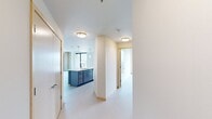 Located at 202 S Pinckney St in the heart of downtown Madison, this modern 2-bedroom, 2-bathroom residence offers a thoughtfully designed single-level layout with contemporary finishes throughout. Light-toned luxury vinyl plank flooring flows seamlessly across the open-concept living, dining, and kitchen areas, creating a bright and cohesive feel. The kitchen is a standout feature, showcasing a large quartz-topped island with an undermount sink, two-tone cabinetry in white and steel blue, a white tile backsplash, and stainless steel appliances, all illuminated by pendant lighting. Floor-to-ceiling windows flood the living areas with natural light and offer impressive views of the downtown Madison skyline. An exposed concrete structural column adds an industrial accent to the living space. The primary bedroom is generously sized, with large windows framing urban views and a ceiling fan for comfort. The second bedroom features clean white walls and light flooring, offering a versatile and bright space. Both bathrooms are finished with wide-format vanities, framed mirrors, and brushed nickel hardware. A dedicated closet and well-distributed floor plan round out this polished urban residence.