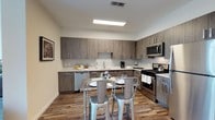 Located at 100 Commons Park North in Stamford, Connecticut, this two-bedroom, two-bathroom residence with a den offers a well-appointed single-floor layout designed for comfortable, modern living. The kitchen is a standout feature, showcasing contemporary wood-grain cabinetry in a warm gray-brown tone, contrasted by clean white countertops. Stainless steel appliances — including a gas range, built-in microwave, and dishwasher — provide a sleek, functional cooking environment. Hardwood-style flooring runs throughout, adding warmth and continuity to the space. A dining area within the kitchen accommodates casual meals with ease. The den provides flexible space suitable for a home office, reading nook, or additional guest area. The two full bathrooms offer convenience for residents and guests alike. The overall design aesthetic is clean and contemporary, with neutral tones and modern fixtures that create a bright, cohesive ambiance throughout the home. Situated in Stamford's Commons Park neighborhood, the residence benefits from its proximity to waterfront parks, dining, and commuter access, making it an ideal home for those seeking both comfort and convenience.