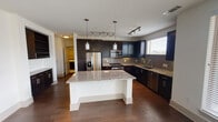 This single-floor residence in Grapevine, Texas offers a well-designed open-concept layout that seamlessly connects the kitchen, dining, and living areas. The kitchen is a standout feature, showcasing rich dark cabinetry, granite countertops, a large central island with pendant lighting, a gray subway tile backsplash, and a full suite of stainless steel appliances including a French door refrigerator, gas range, microwave, and dishwasher. Track lighting throughout enhances the modern aesthetic.

The living area is bright and welcoming, with expansive corner windows that flood the space with natural light and offer views of the surrounding greenery. Rich hardwood flooring runs throughout the main living areas, while a ceiling fan adds comfort and functionality. Direct access to an outdoor balcony extends the living space further.

The bedrooms are carpeted for comfort, each featuring a ceiling fan and windows that bring in natural light. The bathrooms are finished with clean, light tile flooring, dark wood vanities, white countertops, large mirrors, and shower-tub combinations with chrome fixtures. A spacious double-sink vanity in the primary bathroom adds a practical luxury touch. The overall ambiance is clean, contemporary, and move-in ready.