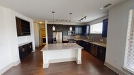 This single-floor residence in Grapevine, Texas offers a well-designed open-concept layout that seamlessly connects the kitchen, dining, and living areas. The kitchen is a standout feature, showcasing rich dark cabinetry, granite countertops, a large central island with pendant lighting, a gray subway tile backsplash, and a full suite of stainless steel appliances including a French door refrigerator, gas range, microwave, and dishwasher. Track lighting throughout enhances the modern aesthetic.

The living area is bright and welcoming, with expansive corner windows that flood the space with natural light and offer views of the surrounding greenery. Rich hardwood flooring runs throughout the main living areas, while a ceiling fan adds comfort and functionality. Direct access to an outdoor balcony extends the living space further.

The bedrooms are carpeted for comfort, each featuring a ceiling fan and windows that bring in natural light. The bathrooms are finished with clean, light tile flooring, dark wood vanities, white countertops, large mirrors, and shower-tub combinations with chrome fixtures. A spacious double-sink vanity in the primary bathroom adds a practical luxury touch. The overall ambiance is clean, contemporary, and move-in ready.