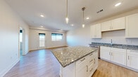 Located in Elkhorn, Nebraska, this well-appointed 1-bedroom, 1-bathroom unit offers a thoughtfully designed open-concept layout with modern finishes throughout. The kitchen serves as the heart of the home, showcasing crisp white shaker cabinetry, granite countertops, a generously sized center island with pendant lighting, and a full suite of stainless steel appliances including a refrigerator, range, microwave, and dishwasher. Light wood-style flooring flows seamlessly through the kitchen and living areas, enhancing the clean, contemporary aesthetic. The living room benefits from abundant natural light, with large windows and a glass-panel door opening to a private balcony that offers expansive views of the surrounding Elkhorn landscape. The bedroom is a comfortable retreat featuring plush carpeting, a ceiling fan, and a large window that frames scenic open-sky views. A dedicated closet provides practical storage. The full bathroom continues the refined design language with granite countertops, white cabinetry, and a tub-shower combination, all finished with light wood-style flooring. Recessed lighting throughout the unit adds to the bright, airy ambiance, making this a polished and functional living space.