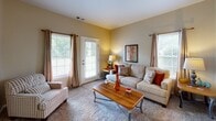 Located at 2900 Woods Edge Dr in Painted Post, NY, this single-floor residence offers a thoughtfully laid-out living space designed for comfort and functionality. The living room is bright and welcoming, featuring plush carpeting, multiple windows dressed with elegant curtains, and a glass door that brings in natural light and views of the surrounding greenery — creating an inviting atmosphere for relaxation or entertaining.

The kitchen is well-appointed with warm wood cabinetry, granite-style countertops, stainless steel appliances including a range, microwave, and refrigerator, and a central island that provides additional prep and dining space. Hardwood-style flooring grounds the kitchen and transitions naturally into the adjacent dining area, where a pendant chandelier illuminates a cozy dining nook filled with natural light from surrounding windows.

The bedroom is a serene retreat, carpeted for warmth and comfort, with a large window offering outdoor views and ample space for rest and storage. The bathroom is well-finished, featuring tile flooring, a granite-topped vanity with wood cabinetry, and a tub-shower combination. A dedicated home office rounds out the layout, complete with carpeted flooring, a bright window, and sufficient space for a full desk setup — ideal for remote work or study.