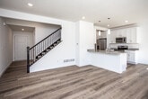 This well-designed two-story home offers a clean, modern aesthetic throughout both levels. The main floor centers around an open-concept living and kitchen area, where warm hardwood-style flooring flows seamlessly underfoot. The kitchen is thoughtfully appointed with crisp white shaker cabinetry, granite-look countertops, a peninsula island with a built-in sink and pendant lighting overhead, and a full suite of stainless steel appliances including a refrigerator, range, microwave, and dishwasher. Recessed lighting brightens the space, and a staircase with black metal balusters provides a modern accent as it leads to the upper level. A half bathroom with hardwood-style flooring is conveniently located on the main floor. Upstairs, multiple bedrooms feature plush wall-to-wall carpeting, ceiling fans, and windows that invite natural light. The upper level is served by a full bathroom with a tub-shower combination, a granite-top vanity, and tile flooring, as well as a primary bathroom featuring a glass-enclosed walk-in shower with white subway tile, a double-sink granite vanity, and matching tile floors. Throughout, the home maintains a bright, neutral palette that creates a fresh and welcoming atmosphere.