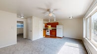 Located at 6900 S 125th St in Seattle, WA, this one-bedroom, one-bathroom unit offers a practical and comfortable single-floor layout. The living area is generously carpeted and bathed in natural light through a large picture window that frames lush, verdant views of mature trees — a serene backdrop that brings the outdoors in. A ceiling fan adds both functionality and a finishing touch to the space. Baseboard heating runs throughout, ensuring consistent warmth across the unit.

The kitchen is efficiently designed with warm honey-toned wood cabinetry, granite-look countertops, and durable hardwood-style flooring. It is equipped with a full suite of white appliances, including a refrigerator, electric range, and under-cabinet ventilation, making it a practical space for everyday cooking.

The bedroom features plush carpeting, a sliding double-door closet offering ample storage, and direct access to the bathroom. The bathroom is finished with hardwood-style flooring, a white vanity with a clean countertop, a window for natural light and ventilation, and a full bathtub and shower combination. Neutral tones and clean finishes throughout the unit create a calm, move-in-ready atmosphere well-suited for comfortable everyday living.