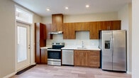 Located at 375 Osprey Lane in Independence, Oregon, this efficiently designed single-floor unit offers a thoughtfully arranged layout that maximizes every square foot. The open-concept main living area seamlessly integrates the living room, dining space, and kitchen into one cohesive zone, creating an airy, functional environment.

The kitchen is a standout feature, outfitted with rich warm-toned wood cabinetry that extends floor to ceiling, providing generous storage. Stainless steel appliances — including an electric range, dishwasher, and a French-door refrigerator with an in-door ice and water dispenser — lend a modern, polished look. White countertops provide clean contrast against the wood tones, and recessed lighting keeps the space bright. A door adjacent to the kitchen opens to a private outdoor balcony, allowing natural light to pour into the living area.

Light-toned plank flooring runs throughout the unit, contributing to a clean, contemporary aesthetic. The bathroom features a well-appointed vanity with matching warm wood cabinetry, white countertops, an undermount sink, and a large mirror. Adjacent to the bathroom is a dedicated closet with hanging storage. The unit also includes a separate laundry area with an electrical panel, completing a practical and well-considered floor plan.
