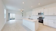 Located at 17224 Auburn Arch Loop in Wimauma, FL, this two-story home offers a clean, modern aesthetic with a bright, neutral palette carried throughout both levels. The ground floor hosts the main living areas, including an open-concept kitchen and living room. The kitchen is a standout feature, outfitted with crisp white shaker cabinetry, a subway tile backsplash, stainless steel appliances, and a central island with an undermount sink — all set atop light-toned tile flooring that extends into the living area. The living room benefits from sliding glass doors that invite natural light and provide outdoor views of the surrounding neighborhood. An attached garage with a dedicated water heater and interior access door completes the lower level. Upstairs, the home's three bedrooms are finished with plush carpet and ceiling fans, each offering natural light through blinds-fitted windows. The spacious primary bedroom provides generous room to furnish comfortably. The bathrooms are finished in a consistent modern style, with the full bath featuring a glass-enclosed walk-in shower with large-format white tile, a white vanity with quartz-style countertop, and light wood-look flooring. Hallways and a dedicated laundry area add practicality to this well-designed home.