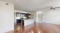 Located at 7145 Reading Rd in Rosenberg, TX, this two-story, one-bedroom, one-bathroom home offers a well-organized layout across two levels, with the main living spaces occupying the upper floor. The open-concept living and kitchen area is anchored by rich hardwood flooring and an abundance of natural light streaming through large double doors with transom windows and surrounding sidelights. The kitchen is a standout feature, showcasing dark espresso cabinetry, stainless steel appliances including a gas range, built-in microwave, and French door refrigerator, along with a granite-topped center island with a sink and pendant lighting above. The living area flows seamlessly from the kitchen, offering a ceiling fan and access to the outdoors. The bedroom is comfortably sized, finished with plush carpet and a ceiling fan, and connects directly to a generous walk-in closet outfitted with multiple shelving rods and built-in shelving units. The full bathroom features tile flooring, a soaking tub with tiled surround, a separate toilet area, and a dark-cabineted vanity with a granite countertop. The ground level provides access to an attached garage with an automatic opener, completing this practical and well-appointed home.