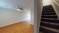 This two-story South Carolina residence offers a functional and well-maintained layout across both floors. The main level features an open living area with warm wood-look flooring, white baseboards, and a ceiling fan with light fixture, creating a bright and comfortable atmosphere. A carpeted staircase connects the two levels, adding a practical design element to the home.

The kitchen is outfitted with white cabinetry, granite-style countertops, stainless steel appliances including a range and refrigerator, and a range hood — providing ample storage and a clean, cohesive aesthetic. A built-in shelving nook adds additional display or storage space.

The upper floor hosts multiple bedrooms, each featuring wood-look flooring in rich tones, ceiling fans, natural light from window treatments with blinds, and neutral wall colors that lend a calm, versatile feel. The rooms vary slightly in flooring tone, from lighter oak hues to deeper walnut finishes.

The bathrooms are neatly designed with granite-topped vanities, white cabinetry, walk-in shower enclosures, and wood-look flooring. Clean white fixtures and brushed nickel hardware complete the polished look. Overall, the space presents a consistent, move-in-ready aesthetic with durable finishes and practical features throughout.