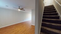 This two-story South Carolina residence offers a functional and well-maintained layout across both floors. The main level features an open living area with warm wood-look flooring, white baseboards, and a ceiling fan with light fixture, creating a bright and comfortable atmosphere. A carpeted staircase connects the two levels, adding a practical design element to the home.

The kitchen is outfitted with white cabinetry, granite-style countertops, stainless steel appliances including a range and refrigerator, and a range hood — providing ample storage and a clean, cohesive aesthetic. A built-in shelving nook adds additional display or storage space.

The upper floor hosts multiple bedrooms, each featuring wood-look flooring in rich tones, ceiling fans, natural light from window treatments with blinds, and neutral wall colors that lend a calm, versatile feel. The rooms vary slightly in flooring tone, from lighter oak hues to deeper walnut finishes.

The bathrooms are neatly designed with granite-topped vanities, white cabinetry, walk-in shower enclosures, and wood-look flooring. Clean white fixtures and brushed nickel hardware complete the polished look. Overall, the space presents a consistent, move-in-ready aesthetic with durable finishes and practical features throughout.
