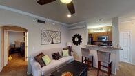 Located at 2805 E 97th Ct in Tulsa, Oklahoma, this single-floor residence offers a well-designed layout that balances comfort and functionality throughout. The open-concept living area is a welcoming focal point, finished with plush carpeting, crown molding, and a ceiling fan overhead. Decorative wall art and an arched passageway add character, while the space flows naturally into the kitchen via a granite-topped breakfast bar with bar seating. The galley-style kitchen is well-appointed with warm wood cabinetry, granite countertops, stainless steel appliances including a refrigerator and microwave, and hardwood-style flooring that adds a polished touch. A built-in wine rack above the cabinetry provides an elegant accent. The bedrooms are carpeted and comfortable, each featuring ceiling fans and windows that allow natural light to fill the rooms. The primary bedroom offers ample space with framed wall art and closet access. Two full bathrooms serve the residence, each featuring granite vanity countertops with dual or single sinks, wood cabinetry, and tub-shower combinations. The consistent use of granite surfaces and warm-toned finishes throughout creates a cohesive and inviting atmosphere across the entire home.