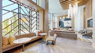 This generously sized single-floor club room in Annapolis, Maryland is a thoughtfully designed communal space that seamlessly blends social, recreational, and functional areas under one roof. The interior is characterized by soaring double-height ceilings, warm wood-toned finishes, and herringbone-patterned tile flooring that flows continuously throughout, creating a cohesive and sophisticated aesthetic.

The main lounge area anchors the space with a large sectional sofa arranged around a wood-framed television feature wall, flanked by decorative laser-cut metallic panels and marble accents. Vertical wood slat detailing and sculptural pendant lighting add refinement and visual depth. A built-in window nook with a geometric wood screen provides an intimate seating alcove bathed in natural light.

The game zone accommodates a shuffleboard table and pool table beneath dramatic cluster pendant lighting and a herringbone-accented feature wall with a mounted TV. A dedicated workspace runs along floor-to-ceiling windows overlooking an outdoor courtyard, offering ample natural light and outdoor views. A dining area with bar-height seating and bold geometric wall art completes the layout, while the overall palette of neutral tones, warm woods, and teal accents delivers a polished, resort-inspired ambiance throughout.