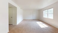 This single-story, three-bedroom unit offers a practical and straightforward layout designed for comfortable everyday living. The floor plan, visible in the 3D overview, reveals a well-organized arrangement of rooms that flow logically from one space to the next.

The spacious living area is finished with neutral-toned carpet and benefits from ample natural light streaming through a large window. The room connects directly to the kitchen, which features warm wood-toned cabinetry, light countertops, a tile floor, and white appliances including a refrigerator, dishwasher, and range. An overhead light fixture provides additional illumination in this functional cooking space.

The three bedrooms are each finished with plush carpet and crisp white walls, maintaining a clean and consistent aesthetic. Each room includes windows that frame views of surrounding greenery, filling the spaces with natural light and a connection to the outdoors.

The bathrooms are finished with tile flooring and include standard fixtures. One bathroom features a full tub-shower combination with chrome hardware, while another includes a vanity with a light countertop and wood cabinetry. Throughout, the unit maintains a clean, neutral palette that serves as a versatile backdrop for a variety of furnishing styles.