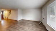 This two-bedroom, two-bathroom unit at 9009 S Hosmer St in Tacoma, WA is spread across two floors, offering a practical and well-organized layout. The main floor features a combined living and dining area filled with natural light from a large front-facing window, complemented by wood-look laminate flooring and a textured ceiling. Baseboard heating is present throughout, ensuring year-round comfort. The galley-style kitchen includes white cabinetry, tile countertops, a stainless steel sink, and an electric range, with a window overlooking greenery outside. A hallway with tile flooring connects the main living areas, and a full bathroom on this level features a soaking tub and shower combo, wood-look flooring, and a tiled vanity with warm wood cabinetry. The second floor hosts both bedrooms, each finished with plush carpet, textured ceilings, baseboard heating, and windows that bring in natural light. The primary bedroom includes a sliding wood-panel closet door and additional storage access. A second bathroom on this level doubles as a laundry room, adding everyday convenience. Multiple closets throughout the unit provide ample storage. The space offers a clean, functional design suited for comfortable everyday living.