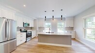 Located at 10 Waterfall Dr in Saco, Maine, this well-appointed 2-bedroom, 2-bathroom single-floor home offers a thoughtfully designed layout with modern finishes throughout. The open-concept kitchen serves as the heart of the home, showcasing white shaker cabinetry with crown molding, a gray center island with a undermount sink, quartz countertops, stainless steel appliances, a subway tile backsplash, and pendant lighting. Large windows flood the space with natural light and offer views of the surrounding landscape. Light-toned hardwood-style flooring runs through the main living areas, connecting the kitchen, living room, and hallways seamlessly. The living area features a sliding glass door leading to a private balcony overlooking lush, wooded scenery. Both bedrooms are carpeted in neutral tones, providing a comfortable retreat; the primary bedroom is generously sized and includes a walk-in closet with wire shelving. The bathrooms are clean and bright, with one featuring a full soaking tub and tiled surround. A dedicated laundry area houses a full-size front-loading washer and dryer. The home also includes a closet and two hallways that enhance the functional flow of the space, making this a practical and attractive residence in Saco, ME.