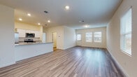 This single-story home offers a clean, contemporary design characterized by an open-concept living area that flows seamlessly into the kitchen and dining space. Light-toned wood-look flooring extends throughout the main living areas, complementing the warm, neutral wall palette and recessed lighting overhead. Multiple windows along the living room walls invite an abundance of natural light, creating a bright and welcoming atmosphere.

The kitchen serves as a functional centerpiece, featuring white shaker-style cabinetry, granite countertops, and a generously sized island with a built-in sink. Stainless steel appliances, including a refrigerator, range, and microwave, complete the well-appointed space. An adjacent door provides convenient access to additional areas of the home.

The bedrooms are finished with plush carpet flooring and include ample closet space with built-in hanging rods and shelving. Windows in each bedroom allow for natural light and outdoor views. The bathrooms maintain the home's consistent aesthetic with white cabinetry, clean countertops, wood-look tile flooring, and tub-shower combinations with chrome fixtures. Overall, the home presents a cohesive, move-in-ready environment with a modern, understated character throughout.