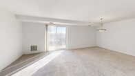 Located at 80 N Portage Path in Akron, Ohio, this two-bedroom, two-bathroom residence offers a thoughtfully arranged single-floor layout. The combined living and dining area is bright and open, featuring plush carpeting, neutral white walls, and a large sliding glass door with vertical blinds that fills the space with natural light and provides access to an outdoor view. A pendant light fixture distinguishes the dining area, adding a classic touch to the space.

The kitchen is well-appointed with warm-toned wooden cabinetry, dark granite-style countertops, and white appliances including a range, microwave, dishwasher, and refrigerator. Light wood-style flooring runs throughout the kitchen, lending a clean, modern contrast to the cabinetry.

Both bedrooms are carpeted and generously sized, with windows dressed in vertical blinds that allow ample natural light. The primary bedroom is notably spacious and includes a built-in vanity area with a mirror and drawers — a functional and charming feature. The two bathrooms offer practical finishes, including a walk-in glass-door shower in one and classic tile accents. With five closets distributed throughout, storage is plentiful. Two hallways connect the layout efficiently, and the welcoming entrance completes this well-organized home.