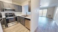 Located on Indian School Road in Albuquerque, New Mexico, this one-bedroom, one-bathroom unit offers a thoughtfully designed single-level layout. Light wood-style flooring runs throughout the main living areas, complementing the clean, neutral color palette found across the space.

The open kitchen and living room area forms the heart of the unit. The kitchen features grey shaker-style cabinetry, light countertops, and a full suite of stainless steel appliances including an electric range, over-the-range microwave, and dishwasher. A pass-through window connects the kitchen to the living area, enhancing the open feel. The living room is generously sized, fitted with a ceiling fan, and anchored by a sliding glass door with vertical blinds that opens to an outdoor area, allowing ample natural light.

The bedroom is a comfortable size, finished with plush carpet flooring, a ceiling fan, and a large window with vertical blinds that invites natural light and outdoor views. An attached closet provides dedicated storage with built-in shelving and hanging rods, finished with the same soft carpeting.

The bathroom offers a clean, functional design with a vanity featuring grey cabinetry, light countertops, and a tiled tub-shower combination. The entrance area provides a welcoming transition into the unit, completing this efficient and well-maintained Albuquerque residence.