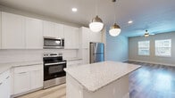 Located at 7551 Narcoossee Rd in Orlando, FL, this well-appointed 2-bedroom, 2-bathroom residence offers a thoughtfully designed single-floor layout with a clean, contemporary aesthetic. Light wood-style flooring runs throughout the entire space, complemented by soft neutral wall tones and crisp white trim that create a bright, cohesive atmosphere.

The open-concept kitchen and living area serves as the heart of the home. The kitchen is outfitted with sleek white shaker-style cabinetry extending to the ceiling, a white subway tile backsplash, stainless steel appliances including a refrigerator, range, and over-the-range microwave, and a generous granite-topped island ideal for dining or meal prep. Stylish globe pendant lights in brushed gold hang above the island, adding a modern touch. The adjoining living area features a ceiling fan and windows that invite natural light.

The spacious primary bedroom comfortably accommodates large furnishings and includes a ceiling fan and closet access. Its en-suite bathroom features a granite-topped vanity with undermount sink, white cabinetry, and a glass-enclosed walk-in shower. The second bedroom is bright with dual windows offering outdoor views and its own ceiling fan. The second bathroom mirrors the same refined finishes, featuring a granite vanity and a tiled tub-shower combination. Three closets provide ample storage throughout.