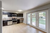 Located at 7400 Parkwood Terrace in Falls Church, VA, this ground-floor unit offers three bedrooms and two full bathrooms across a single level of thoughtfully laid-out living space. Light-toned hardwood flooring runs throughout, lending a clean and cohesive look to every room.

The living room is open and airy, featuring neutral gray walls, white trim, and a sliding glass door that leads directly to a concrete patio overlooking a generous, tree-shaded lawn — ideal for relaxing or entertaining outdoors.

The kitchen is well-equipped with dark espresso-toned shaker cabinets, granite-style countertops, and a full suite of stainless steel appliances including a refrigerator, gas range, microwave, and dishwasher. Bright overhead lighting enhances the functional layout.

The primary bedroom offers a comfortable footprint with a large bifold closet providing ample storage. The additional bedrooms share similar neutral tones and light flooring, keeping the spaces versatile and easy to furnish.

Both bathrooms are finished with light hardwood floors, clean white tilework, and full tub-shower combinations. One bathroom features a dark vanity with brushed nickel hardware, complementing the white tile accented with a dark mosaic border stripe. The overall aesthetic throughout the unit is clean, modern, and move-in ready.
