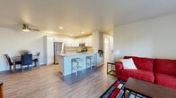 Located at 960 County Road B in Shawano, Wisconsin, this well-appointed two-bedroom, two-bathroom single-floor unit offers a thoughtfully designed layout with modern finishes throughout. The open-concept kitchen and living area serves as the heart of the home, featuring crisp white shaker-style cabinetry, light granite countertops, a full suite of stainless steel appliances, and a central island with bar seating — ideal for both everyday meals and entertaining. Durable wood-look flooring runs through the main living areas, complementing the bright, neutral color palette.

The living room is generously sized with large sliding glass doors that flood the space with natural light and provide direct outdoor views of the surrounding greenery. The primary bedroom offers a comfortable retreat with plush carpeting, a ceiling fan, a dedicated window for natural light, and access to a private bathroom featuring white cabinetry and granite countertops. A walk-in closet with wire shelving provides ample storage. The second bedroom is equally well-lit with an exterior-facing window and its own closet. Both bathrooms echo the clean, modern aesthetic found throughout the unit, with consistent finishes and hardwood-style flooring.