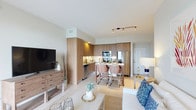 This single-floor residence offers a thoughtfully designed open-concept layout that seamlessly connects the kitchen, dining, and living areas. The kitchen is outfitted with warm wood-grain cabinetry extending floor to ceiling, stainless steel appliances including a French door refrigerator, electric range, and built-in microwave, complemented by granite countertops and light tile flooring. A central kitchen island with seating serves as a natural dining hub, ideal for casual meals or entertaining. The living area features a bright, neutral palette with ample room for comfortable furnishings.

The bedrooms are finished in soft, muted blue-gray tones that evoke a coastal ambiance. Each bedroom includes natural light through large windows with curtain panels, ceiling fans, and carpeted flooring. At least one bedroom features a walk-in closet, enhancing storage capacity.

Two bathrooms are present, each featuring wood-grain vanity cabinetry and granite countertops. One bathroom includes a walk-in glass-enclosed shower with tile surround, while the other features a shower-tub combination with a large vanity mirror. Both bathrooms maintain a clean, contemporary aesthetic consistent with the overall design of the residence.