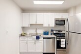 Located at 2000 N Adams St, Unit 417, in Arlington, Virginia, this thoughtfully designed unit offers a practical and comfortable single-floor layout. Light-toned luxury vinyl plank flooring runs throughout, contributing to a clean, cohesive aesthetic complemented by neutral white walls and crisp white trim.

The combined living and dining area is bright and open, anchored by a large window that invites natural light and offers views of surrounding greenery. The space is versatile, accommodating both relaxing and dining arrangements with ease.

The kitchen is well-appointed, featuring white shaker-style cabinetry, granite-look countertops, and a full suite of stainless steel appliances including a gas range, microwave, dishwasher, and refrigerator. A skylight-style flush ceiling fixture enhances the brightness of the cooking space.

The bathroom is efficiently laid out with light wood-tone flooring, a vanity with granite-look countertops, white cabinetry, and a tub/shower combination. Four closets distributed throughout the unit provide generous storage capacity, a notable feature for a space of this size.

A hallway connects the key areas of the unit, and the entry door is equipped with a smart lock. The overall design is clean and modern, making for a well-organized, move-in ready space in a prime Arlington location.