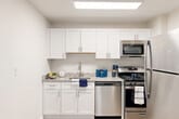 Located at 2000 N Adams St, Unit 417, in Arlington, Virginia, this thoughtfully designed unit offers a practical and comfortable single-floor layout. Light-toned luxury vinyl plank flooring runs throughout, contributing to a clean, cohesive aesthetic complemented by neutral white walls and crisp white trim.

The combined living and dining area is bright and open, anchored by a large window that invites natural light and offers views of surrounding greenery. The space is versatile, accommodating both relaxing and dining arrangements with ease.

The kitchen is well-appointed, featuring white shaker-style cabinetry, granite-look countertops, and a full suite of stainless steel appliances including a gas range, microwave, dishwasher, and refrigerator. A skylight-style flush ceiling fixture enhances the brightness of the cooking space.

The bathroom is efficiently laid out with light wood-tone flooring, a vanity with granite-look countertops, white cabinetry, and a tub/shower combination. Four closets distributed throughout the unit provide generous storage capacity, a notable feature for a space of this size.

A hallway connects the key areas of the unit, and the entry door is equipped with a smart lock. The overall design is clean and modern, making for a well-organized, move-in ready space in a prime Arlington location.