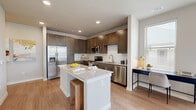 Located at 1239 E Borgfeld Dr in San Antonio, TX, this thoughtfully designed one-bedroom, one-bathroom residence offers a comfortable and modern living experience across a single floor. Light wood-style flooring runs throughout, tying the spaces together with a clean, cohesive aesthetic.

The open-concept kitchen and living area serves as the heart of the home. The kitchen is outfitted with rich dark-stained cabinetry, a white subway tile backsplash, granite countertops, and a full suite of stainless steel appliances, including a refrigerator with ice maker, range, microwave, and dishwasher. A central island with a granite top and bar seating provides additional prep and dining space. The adjacent living room is bathed in natural light from a wraparound bank of windows fitted with blinds, and features a ceiling fan overhead.

A well-lit hallway with recessed lighting connects the living areas to the private quarters, with a louvered closet door and additional storage accessible along the way. The bedroom is a calm, neutral retreat with a ceiling fan, natural light from dual windows, and ample room. It connects directly to a walk-in closet outfitted with wire shelving systems for organized storage.

The bathroom features a soaking tub with a white subway tile surround, a granite-topped vanity with dark cabinetry, and wood-style flooring, completing this polished and functional residence.