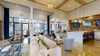 Located at 440 Cane Hill Rd in Nashville, TN, this single-story amenity space is thoughtfully designed to offer a variety of social and entertainment experiences. The grand entry foyer sets the tone with soaring ceilings, polished concrete floors, stacked-stone accent columns, and an eye-catching chandelier that draws the eye upward.

The main clubroom is a standout, boasting a reclaimed wood feature wall, sleek bar with stainless steel refrigeration, pendant lighting, and a large island with bar seating — all beneath a dramatic tray ceiling with gold trim. An adjacent lounge area features a coffered ceiling with reclaimed wood inlays, polished concrete floors, elegant drapery, and a shuffleboard table alongside curated seating arrangements.

The dedicated screening room offers tiered blue leather club chairs, a built-in tufted banquette, patterned carpet, a ceiling-mounted projector, and a large projection screen framed by rich navy curtains — delivering a true cinematic experience.

The covered outdoor terrace is furnished with vibrant blue sectional seating, a ceiling fan, a stacked-stone accent wall with a mounted TV, and wrought-iron fencing that opens to outdoor views. Together, these spaces create a polished, resort-inspired atmosphere ideal for gathering and entertaining.