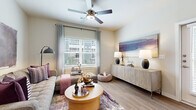 This single-story unit offers a thoughtfully designed layout across one floor, incorporating a living room, kitchen, bedroom, bathroom, and closet. The living room serves as the heart of the space, featuring wood-style plank flooring, a ceiling fan, and a large window that fills the room with natural light and provides outdoor views. The open, airy feel is complemented by neutral wall tones throughout.

The kitchen is outfitted with dark espresso cabinetry reaching toward the ceiling, stainless steel appliances including a full-size refrigerator, gas range, and microwave, as well as light quartz countertops. A peninsula with bar seating connects the kitchen to the living area, enhancing the open-concept flow. A louvered closet door near the entry provides additional storage.

The generously sized bedroom accommodates a large bed comfortably, benefits from its own ceiling fan and window, and connects directly to the bathroom. The bathroom features dark wood vanity cabinetry, quartz countertops, a large mirror, marble-style tile flooring, and a soaking tub with a marble-surround shower enclosure, offering a clean, refined aesthetic throughout.