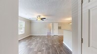 This single-floor, 1-bedroom, 1-bathroom residence offers a thoughtfully designed layout that maximizes functionality and comfort. The open-concept living, dining, and kitchen area serves as the heart of the home, featuring wood-look flooring, crown molding, a textured ceiling, and a ceiling fan with light fixture. Large windows allow natural light to pour in, offering pleasant outdoor views of surrounding greenery. A door provides direct exterior access from the living area.

The galley-style kitchen is well-equipped with white shaker cabinetry, granite-look countertops, a mosaic tile backsplash, black appliances including a range and refrigerator, a stainless steel dishwasher, and a double basin sink — all finished with matching wood-look flooring.

The bedroom is a comfortable, carpeted retreat featuring a textured ceiling, a window with blinds, and ample space for furnishings. A dedicated closet provides organized storage.

The bathroom includes white shaker vanity cabinetry with granite-look countertops, a large mirror, a full tub/shower combination, and rich wood-look flooring. The dedicated laundry room is equipped with utility hookups, overhead wire shelving, and matching flooring, completing this practical and cohesive living space.