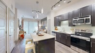 Located at 5522 Maple Ave in Dallas, TX, this one-bedroom, one-bathroom residence offers a well-designed single-floor layout that maximizes every square foot. The open-concept kitchen and living area serves as the heart of the home, featuring dark espresso cabinetry, a light tile backsplash, stainless steel appliances, and a central island with bar seating — ideal for casual dining or entertaining. Track lighting and pendant fixtures illuminate the space with a modern touch, while wood-look flooring runs throughout the main living areas. The living room flows seamlessly from the kitchen, bathed in natural light from large sliding glass doors that lead to an outdoor space. The bedroom is a comfortable retreat with soaring ceilings, plush carpeting, a large window, and direct access to a walk-in closet equipped with built-in shelving. The bathroom features tile flooring, a tub-shower combination, and opens directly into the walk-in closet for added convenience. Additional highlights include three closets, a dedicated laundry area, and a utility room, providing generous storage throughout. The overall ambiance is bright, clean, and modern — a functional and stylish home in Dallas.