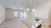 This thoughtfully designed 2-bedroom, 2-bathroom residence offers a comfortable and functional single-floor layout. The open-concept kitchen and living area serves as the heart of the home, where a large island with a stainless steel sink and light quartz countertops takes center stage, illuminated by a trio of stylish pendant lights. White cabinetry pairs with stainless steel appliances, including a refrigerator, range, and microwave. The adjoining living room features plush wall-to-wall carpeting, a ceiling fan, and direct access to the outdoors through a glass-panel door flanked by windows that invite natural light. A dedicated closet off the kitchen provides additional storage. The primary bedroom is a generously sized retreat with a ceiling fan, carpeted flooring, and windows offering outdoor views. The second bedroom mirrors this comfortable aesthetic. Both bathrooms are well-appointed; one features warm hardwood-style flooring, a wide vanity with grey countertops, white cabinetry, a large mirror, and a tiled walk-in shower. A dedicated laundry room with shelving and hardwood-style flooring adds everyday convenience. A hallway connects all areas of the home, creating a cohesive and easy-to-navigate floor plan throughout.
