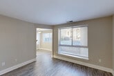 Located in Burtonsville, Maryland, this 1-bedroom, 1-bathroom residence offers a practical and comfortable single-floor layout with clean, modern finishes throughout. The living room is an open, welcoming space featuring durable wood-look flooring, neutral warm-gray walls, crisp white trim, and a large window with blinds that invites ample natural light and outdoor views. The space flows naturally into the kitchen, which is well-equipped with white cabinetry, stone-look countertops, a white electric range, and a subway tile backsplash. A pendant light fixture and a window overlooking the exterior make the kitchen feel bright and functional. The spacious bedroom offers plush carpeting, neutral walls, and a window that provides soft natural light, creating a calm and restful atmosphere. The bathroom is finished with a wide quartz-style vanity countertop, a large framed mirror, brushed nickel fixtures, wood-look flooring, and a tub-shower combination — combining practicality with a clean, updated aesthetic. Throughout the residence, consistent neutral tones and modern finishes create a cohesive and move-in-ready environment suited for comfortable everyday living.