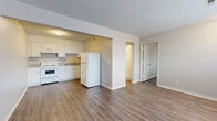 Located at 256 E Allen St in Valley Center, Kansas, this one-bedroom, one-bathroom unit offers a practical and efficiently designed single-floor layout. Wood-look flooring runs consistently throughout the space, providing a cohesive and easy-to-maintain finish. Textured ceilings are present in each room, adding a classic touch to the interior.

The combined kitchen and living area forms the heart of the unit. The kitchen features white cabinetry with ample upper and lower storage, a white electric range, a double sink, and a full-size refrigerator, all set against neutral-toned walls. The adjacent living area is open and functional, with a front entry door and a window that allows natural light to brighten the room.

The bedroom is a well-proportioned private retreat, equipped with a ceiling fan with light fixture and a window fitted with blinds that provide both natural light and privacy. The room also includes a closet, offering useful storage.

A hallway connects the main living areas to the bathroom, which features tile wall accents, providing a clean and durable finish. The overall color palette of warm grays and whites creates a neutral, move-in-ready atmosphere throughout this straightforward and functional Valley Center residence.