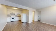 Located at 256 E Allen St in Valley Center, Kansas, this one-bedroom, one-bathroom unit offers a practical and efficiently designed single-floor layout. Wood-look flooring runs consistently throughout the space, providing a cohesive and easy-to-maintain finish. Textured ceilings are present in each room, adding a classic touch to the interior.

The combined kitchen and living area forms the heart of the unit. The kitchen features white cabinetry with ample upper and lower storage, a white electric range, a double sink, and a full-size refrigerator, all set against neutral-toned walls. The adjacent living area is open and functional, with a front entry door and a window that allows natural light to brighten the room.

The bedroom is a well-proportioned private retreat, equipped with a ceiling fan with light fixture and a window fitted with blinds that provide both natural light and privacy. The room also includes a closet, offering useful storage.

A hallway connects the main living areas to the bathroom, which features tile wall accents, providing a clean and durable finish. The overall color palette of warm grays and whites creates a neutral, move-in-ready atmosphere throughout this straightforward and functional Valley Center residence.