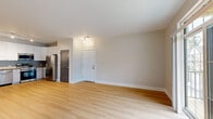 Located at 7025 Fordson Dr in Green, OH, this three-bedroom, one-bathroom unit offers a thoughtfully designed single-floor layout with clean, contemporary finishes throughout. The open living area features light hardwood flooring and neutral-toned walls, with large floor-to-ceiling windows that invite abundant natural light and provide views of the surrounding neighborhood. The kitchen is well-appointed with white shaker-style upper cabinetry, light blue-gray lower cabinets, a classic subway tile backsplash, dark countertops, and a full suite of stainless steel appliances including a dishwasher, range, microwave, and refrigerator. Track and pendant lighting complete the modern aesthetic. The three bedrooms are carpeted for comfort, with the primary bedroom offering a walk-in closet outfitted with multi-tiered wire shelving for ample storage. An additional dedicated closet space with wire shelving provides further organizational options. The bathroom includes a sliding-door walk-in shower, a vanity with granite-style countertop, and matching hardwood flooring. The unit's neutral color palette, modern fixtures, and practical layout make it a functional and comfortable living space.