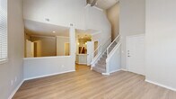 This two-story home is thoughtfully designed to maximize space and natural light across two well-proportioned floors. The main level opens into a striking living room distinguished by soaring vaulted ceilings, a ceiling fan, and multiple windows with blinds that flood the space with natural light. Light wood-tone flooring flows seamlessly throughout the first floor, complementing the neutral, warm-toned walls. A fireplace adds a functional focal point to the living area, while an open pass-through connects to the kitchen. The kitchen features white shaker cabinetry, stainless steel appliances including a range and microwave, a subway tile backsplash, and access to an additional closet for pantry or storage use. A staircase with a white banister leads to the upper level. The second floor hosts the spacious primary bedroom, carpeted for comfort and equipped with a ceiling fan, a generous window with outdoor views, and direct access to a large walk-in closet outfitted with wire shelving on multiple walls. The bathrooms are clean and well-finished, one featuring a soaking tub with subway tile surround and chrome fixtures. A hallway and an additional closet round out the upper floor, providing ample organization and storage throughout the home.