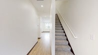 This two-story home in Rochester, Minnesota offers a thoughtfully designed layout across two floors, providing a comfortable and functional living environment. The main level features an open-concept kitchen and living area anchored by a sleek, built-in linear electric fireplace set against a crisp white surround. The kitchen is well-appointed with white shaker-style cabinetry, quartz countertops, stainless steel appliances including a French door refrigerator, electric range, microwave, and dishwasher, along with a central island and contemporary pendant lighting. Light wood-look flooring flows throughout the main level, lending warmth to the bright, neutral interior. The living area receives natural light through sliding glass doors and windows, offering views of the surrounding neighborhood. Upstairs, the home includes three bedrooms, each carpeted and filled with natural light from windows fitted with blinds. The generously sized primary bedroom provides ample space for a full suite of furnishings. Three full bathrooms are finished with white vanities, quartz countertops, and wood-look flooring. A dedicated in-unit laundry room with a full-size washer and dryer adds everyday convenience. Three closets provide practical storage throughout the home.