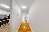 Located at 735 Adams St, Unit 3 in Boston's Dorchester neighborhood, this one-bedroom, one-bathroom residence offers a well-organized single-floor layout designed for comfortable everyday living. Warm-toned hardwood floors run throughout the main living areas and bedroom, lending a cohesive and inviting character to the space. A long, well-lit hallway connects the entrance to the rest of the unit, with clean white walls and recessed lighting creating a bright, welcoming corridor. The kitchen is outfitted with white shaker-style cabinetry, dark granite-style countertops, stainless steel appliances including a dishwasher and electric range, and a stainless steel sink. It opens toward a combined living area that benefits from natural light through large windows with vertical blinds. The bedroom is a comfortable, quiet room featuring dual windows that bring in natural light, baseboard heating, and recessed lighting. The bathroom is finished with marble-patterned floor and wall tiles, a tub-shower combination, a white vanity, and chrome fixtures. Notably, the unit offers an exceptional number of closets — seven in total — providing generous storage options throughout. Baseboard heating is present in multiple rooms.