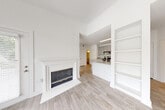 This single-floor residence is designed with an open, airy aesthetic defined by crisp white walls, light-toned wood-style flooring in the main living areas, and an abundance of natural light throughout. The living room serves as the heart of the home, showcasing vaulted ceilings, a ceiling fan with light fixture, and a classic white-mantled fireplace flanked by built-in shelving — ideal for both display and storage. A large window topped with an arched transom pane frames lush outdoor greenery, further enhancing the bright, welcoming atmosphere.

The kitchen is well-appointed with gray shaker-style cabinetry, a white subway tile backsplash, granite countertops, stainless steel appliances, and a peninsula with a built-in sink — offering both functionality and style. The space opens toward the living area, creating a connected, practical layout.

Bedrooms feature plush carpeting, ceiling fans, and generously sized windows that allow ample natural light. The bathroom includes a granite-topped vanity with gray cabinetry, a large mirror, and a clean, neutral finish. Throughout the home, the consistent use of soft tones and quality finishes creates a cohesive and comfortable living environment.