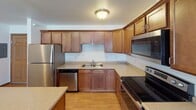 This single-floor unit offers a practical and well-organized layout that balances functionality with comfortable living. The kitchen is a standout feature, equipped with stainless steel appliances including a refrigerator, electric range, built-in microwave, and dishwasher. Warm-toned wood cabinetry extends to the ceiling, providing generous storage, while light countertops and wood-look flooring complete the space. A peninsula counter connects the kitchen to the main living area, creating an open and cohesive flow.

The living area is spacious and open, featuring neutral carpet, a ceiling fan, and access to what appears to be a patio or balcony, allowing for natural light. The layout connects seamlessly to the rest of the unit, with clear sightlines that enhance the sense of openness.

The bedrooms are carpeted and well-proportioned, with at least one featuring a window that brings in natural light. Both bathrooms are finished consistently, each offering a single-sink vanity with wood cabinetry, white countertops, a large mirror with overhead lighting, tile flooring, and a shower-tub combination. The overall ambiance is clean, neutral, and move-in ready.