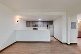 Located at 3185 S Vaughn Way in Aurora, Colorado, this one-bedroom, one-bathroom unit offers a clean, modern layout across a well-organized single floor. Light wood-style flooring flows consistently throughout, complementing the bright white walls and creating a cohesive, contemporary feel.

The combined kitchen and living area forms the heart of the unit. The kitchen is outfitted with gray shaker-style cabinetry, white countertops, and a full suite of stainless steel appliances including a refrigerator, range, microwave, and dishwasher. A peninsula counter separates the kitchen from the open living area, providing both additional workspace and a natural division between the two zones.

A hallway connects the main living space to the private areas of the unit, including the bedroom, bathroom, and closet. The bedroom is generously sized and features a large window that lets in abundant natural light while offering open views of the surrounding landscape — a standout feature of the room. The closet is conveniently located adjacent to the bedroom.

The bathroom is finished in white and includes a full soaking tub with tiled surround. Throughout the unit, recessed lighting and wall sconces provide well-distributed illumination, contributing to the overall clean and functional aesthetic of the space.