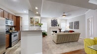 This single-story residence offers a thoughtfully designed layout with a range of distinctive architectural details throughout. The living room serves as the heart of the home, anchored by a white-mantled fireplace framed by arched windows that invite natural light. Crown molding lines the ceiling, and a ceiling fan adds a practical touch to the comfortable, carpeted space.

Adjacent to the living area, the kitchen is equipped with stainless steel appliances, rich wood cabinetry, granite-style countertops, and stone-look tile flooring. A breakfast bar connects the kitchen to the main living areas, creating an open, functional flow. The dining area stands out with its elegant tray ceiling and hardwood flooring, providing a refined setting for gathering.

The primary bedroom features French doors, a ceiling fan, and mirrored closet doors that enhance the sense of space. A second bedroom offers equally comfortable proportions with crown molding and ceiling fan details. The bathroom is finished with slate-style tile on both the floors and tub surround, complemented by warm wood cabinetry and granite-topped vanity. Together, these spaces create a cohesive and well-appointed living environment.