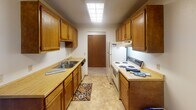 Located at 11811 Zea St NW in Coon Rapids, Minnesota, this single-floor unit offers a straightforward, functional layout designed for comfortable everyday living. The galley-style kitchen is well-equipped, featuring warm honey-toned wood cabinetry lining both walls, laminate countertops, a double stainless steel sink, and white appliances including a range and refrigerator. A skylight-style ceiling fixture provides bright overhead illumination, and tile flooring runs underfoot, adding durability to the space.

The living area is generously proportioned, with neutral carpet, textured ceilings, and a ceiling fan. An accent wall in a deep taupe tone adds visual interest, while vertical blind-covered windows allow natural light to filter in. The open layout connects the living space to the kitchen area, providing a cohesive flow throughout.

The bedroom features carpet flooring, a ceiling fan with light fixture, baseboard heating, and a window dressed with vertical blinds that brings in ample natural light. The full bathroom is clean and functional, offering a wood-toned vanity with a single sink, tile flooring, and a shower-tub combination with a decorative curtain. Throughout the unit, the design is practical and well-maintained, providing a comfortable living environment.