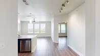 Located in the desirable Steiner Ranch community of Austin, Texas, this thoughtfully designed 2-bedroom, 2-bathroom residence offers a clean, modern aesthetic throughout its comfortable single-floor layout. The open-concept kitchen and living area serves as the heart of the home, showcasing striking dark cabinetry that contrasts beautifully with a large white quartz island, subway tile backsplash, stainless steel appliances, and stylish pendant lighting — all set atop warm wood-style flooring that flows seamlessly through the main living areas. Both bedrooms are bright and welcoming, featuring multiple windows with views of the surrounding greenery and wood-style flooring underfoot. The primary bedroom is generously proportioned and connects to its own en-suite bathroom, which includes a sleek floating vanity with dark wood cabinetry, a framed mirror, and large-format tile flooring. A spacious walk-in closet with built-in shelving and hanging rods provides excellent storage. The second bathroom is equally well-finished, with large neutral tiles and a glass-enclosed shower. Two dedicated closets further enhance the storage options. Neutral tones, clean lines, and abundant natural light from multiple windows give the entire space a bright, airy, and move-in-ready feel.
