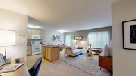 Located at 300 E Marshall St in West Chester, PA, this single-floor residence offers a well-designed open-concept layout that seamlessly connects the kitchen, dining, and living areas into one cohesive and functional space. The kitchen features light maple cabinetry, granite-style countertops, a peninsula breakfast bar, and white appliances including a refrigerator, electric range, microwave, and dishwasher. Hardwood-style flooring grounds the kitchen area, while plush carpet extends throughout the living and dining spaces. The dining area is positioned adjacent to the kitchen and benefits from a large sliding glass door that invites natural light and provides views of the surrounding greenery. The living room is generously proportioned, anchored by a large sliding glass door with vertical blinds that opens to outdoor views and fills the room with natural light. The bedroom offers a comfortable retreat with dual closets providing ample storage, a large window overlooking the outdoors, and soft carpeting. The full bathroom includes a tiled shower-tub combination with grey subway tile surround and light tile flooring. Throughout the unit, neutral tones, clean lines, and consistent finishes create a calm and inviting ambiance well suited to everyday living.