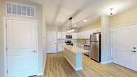 This single-floor residence at 4406 Helen Rd in Jeffersonville, Indiana, offers a thoughtfully designed layout with contemporary finishes throughout. The kitchen serves as a central highlight, featuring crisp white shaker-style cabinetry, light granite countertops, and a full suite of stainless steel appliances, including a range, microwave, dishwasher, and refrigerator. A center island with a pendant light fixture overhead provides additional prep space and a casual gathering point. Light wood-tone luxury vinyl plank flooring runs throughout the main living areas, lending warmth and a clean, cohesive aesthetic.

The living area is bright and open, benefiting from natural light through French doors that lead to an outdoor access point, complemented by a ceiling fan. Bedrooms are carpeted for added comfort and feature windows with exterior views, allowing natural light to fill each room. Ceiling fans in the bedrooms add practical comfort.

The bathroom is well-equipped with a double-sink vanity topped with a white quartz-style countertop, rich dark wood cabinetry with brushed nickel hardware, and a large mirror with overhead lighting. The overall ambiance of this space is clean, modern, and move-in ready, with neutral tones creating a versatile backdrop throughout.